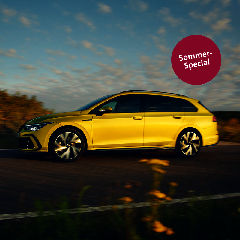 gelber VW Golf Variant fährt bei Abenddämmerung über eine Landstraße